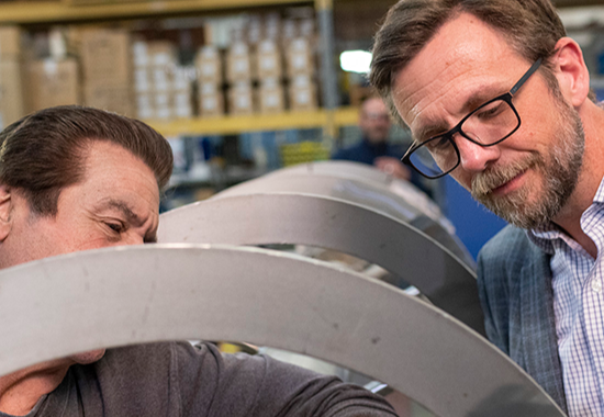 welder and business owner inspecting machinery. 